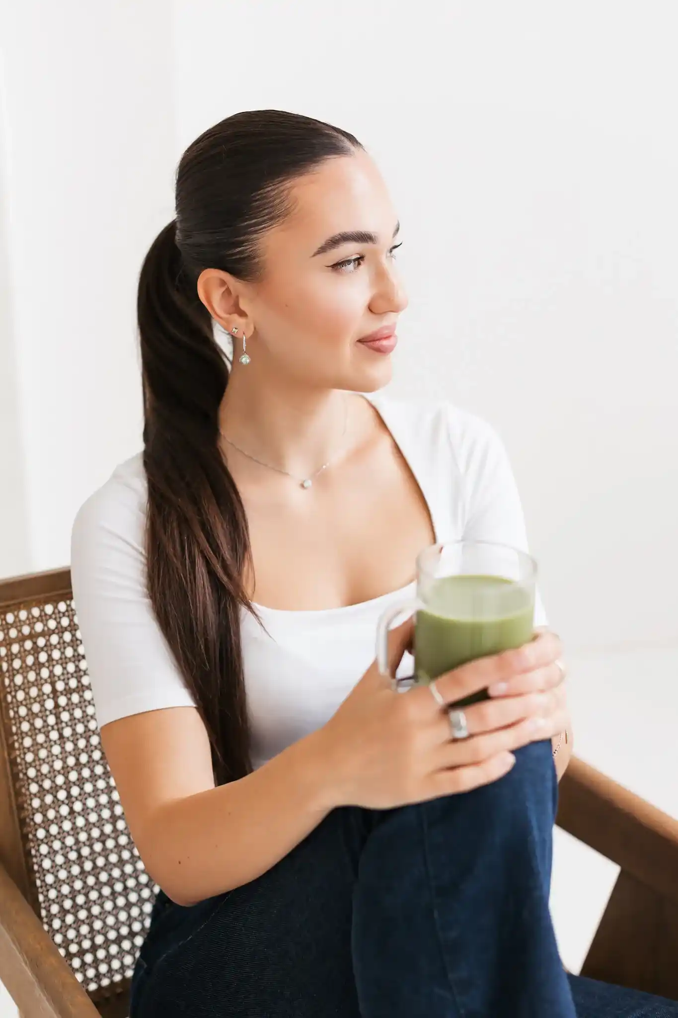 Erika sitting in a rattan chair holding a green juice