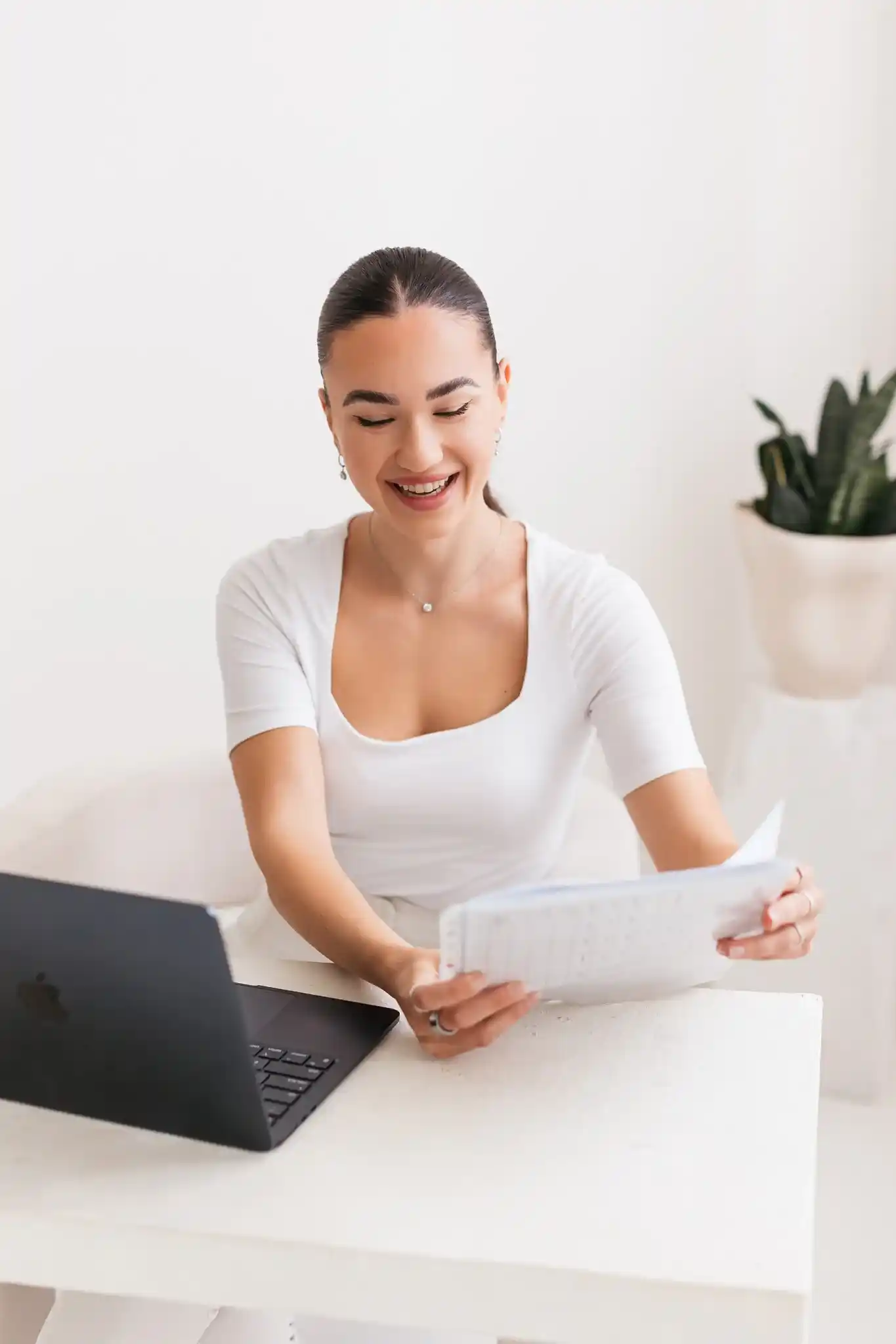 Erika Hudacova, PhD, smiling at her desk while reviewing a client’s notes