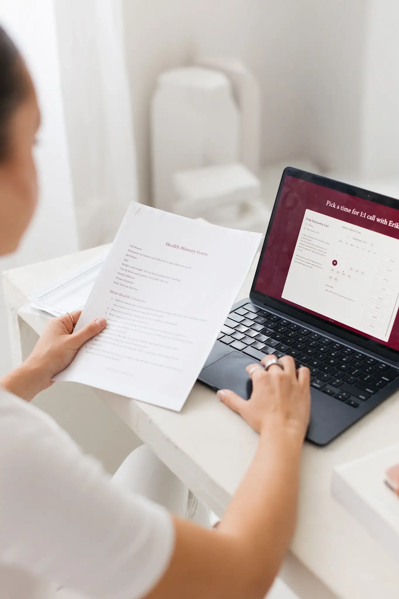 Erika reading a client’s health history form next to her laptop